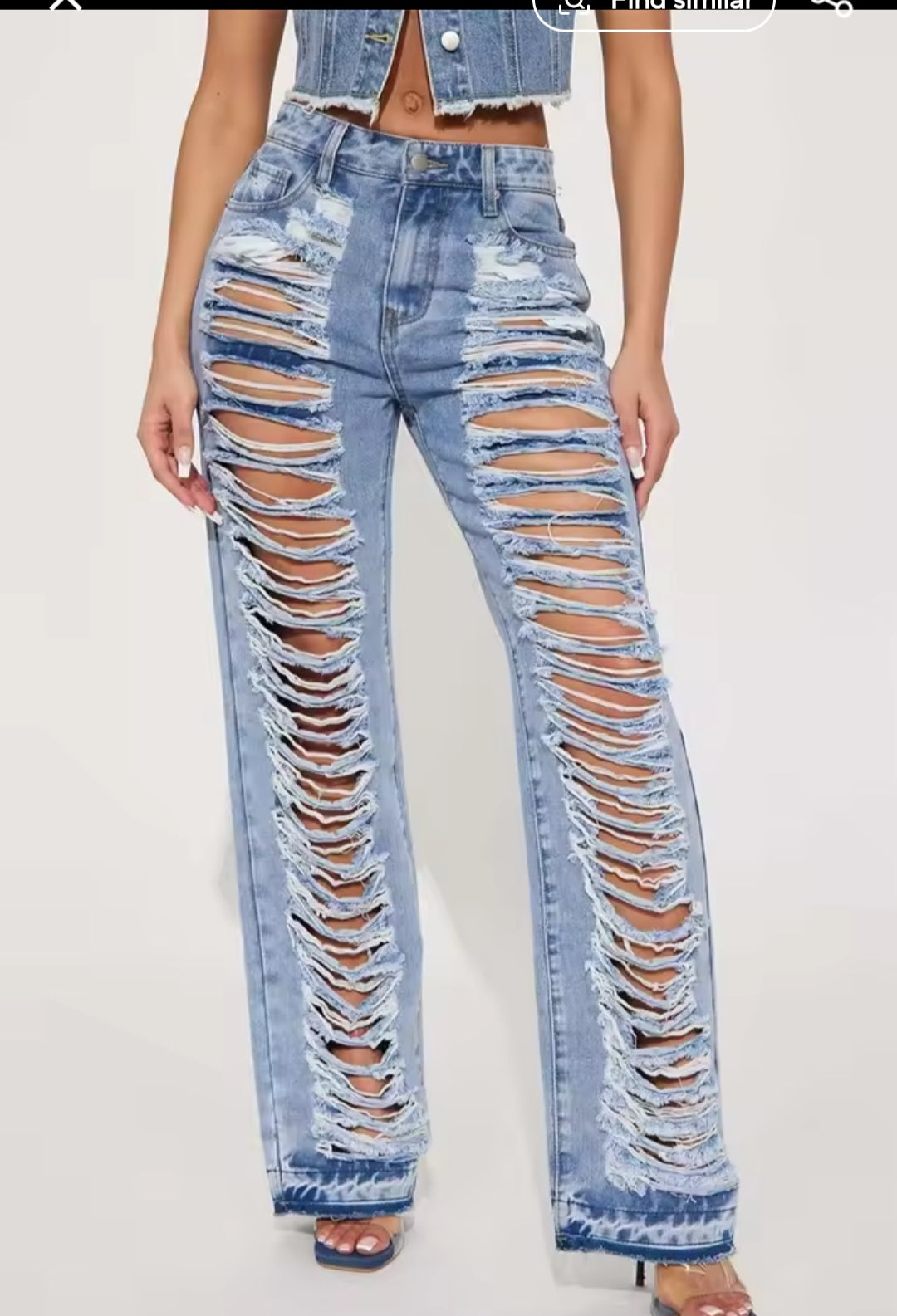 Ripped blue jeans worn by a person on a white background