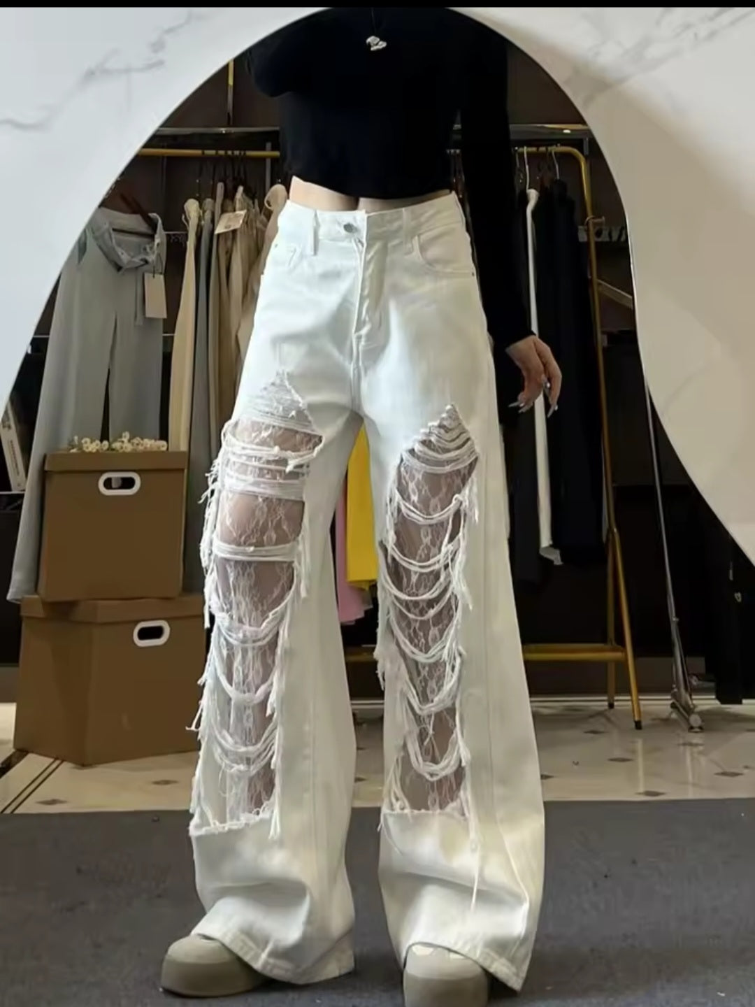 Person wearing white jeans with sheer panels in a clothing store setting