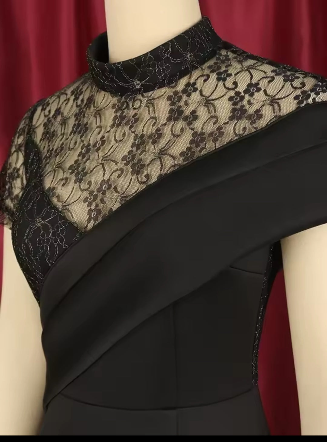 Black lace dress on a mannequin against a red curtain background