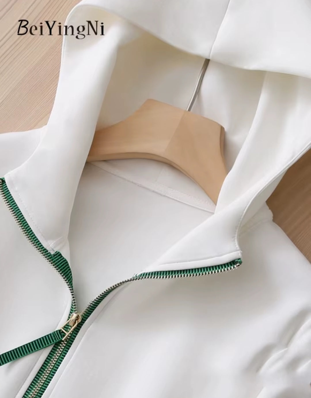 White dress with green trim on a wooden hanger, brand 'BeiYingNi' visible.
