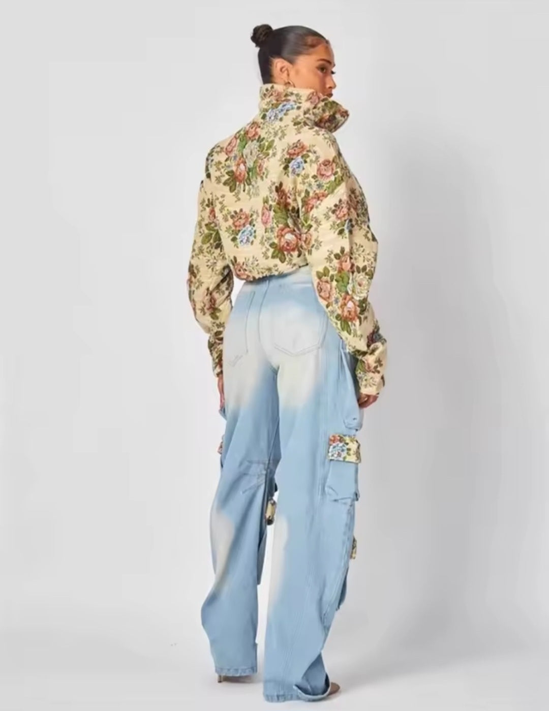 Person wearing a floral jacket and light blue pants on a white background