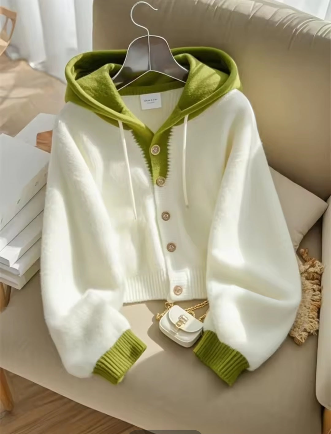 White cardigan with green trim on a beige chair