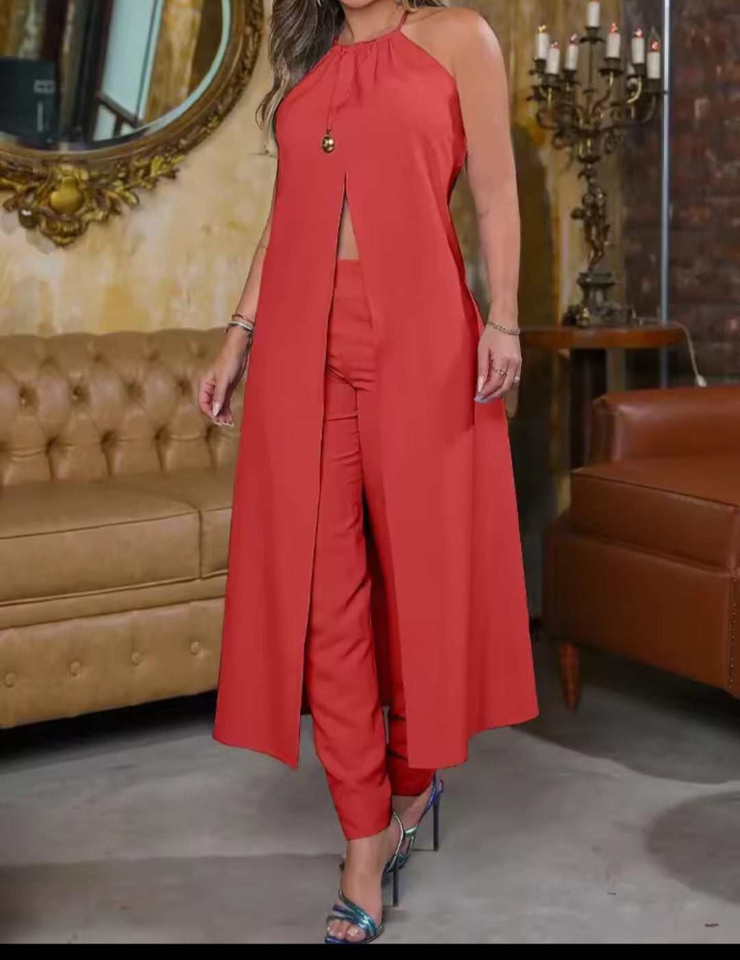 Woman wearing a red jumpsuit in an elegant room with a mirror and candelabra.