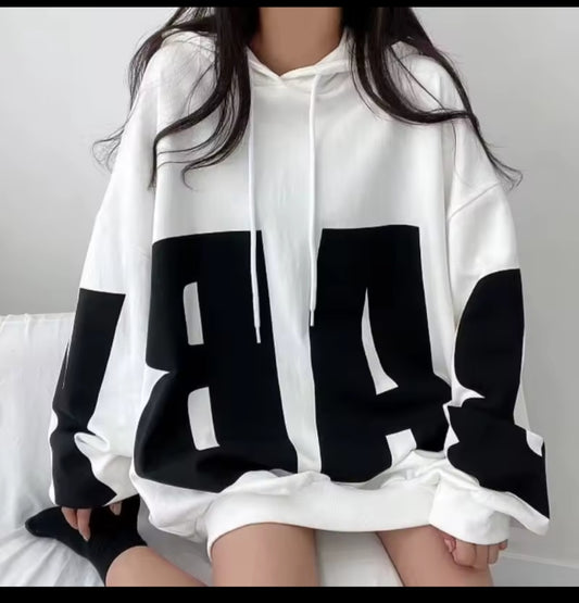 Person wearing a black and white hoodie with abstract design on a plain background