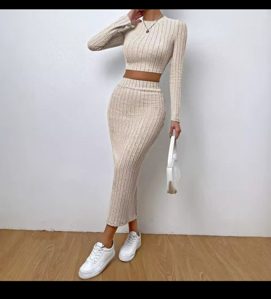 Person wearing a beige ribbed two-piece outfit with white sneakers on a plain background