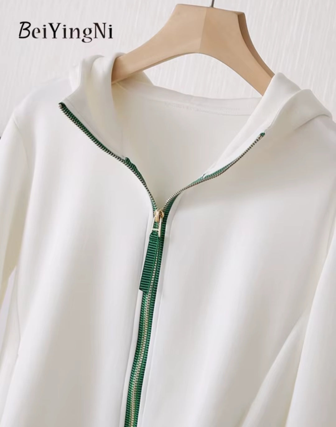 White jacket with green zipper on a hanger, featuring the brand 'BeiYingNi'.