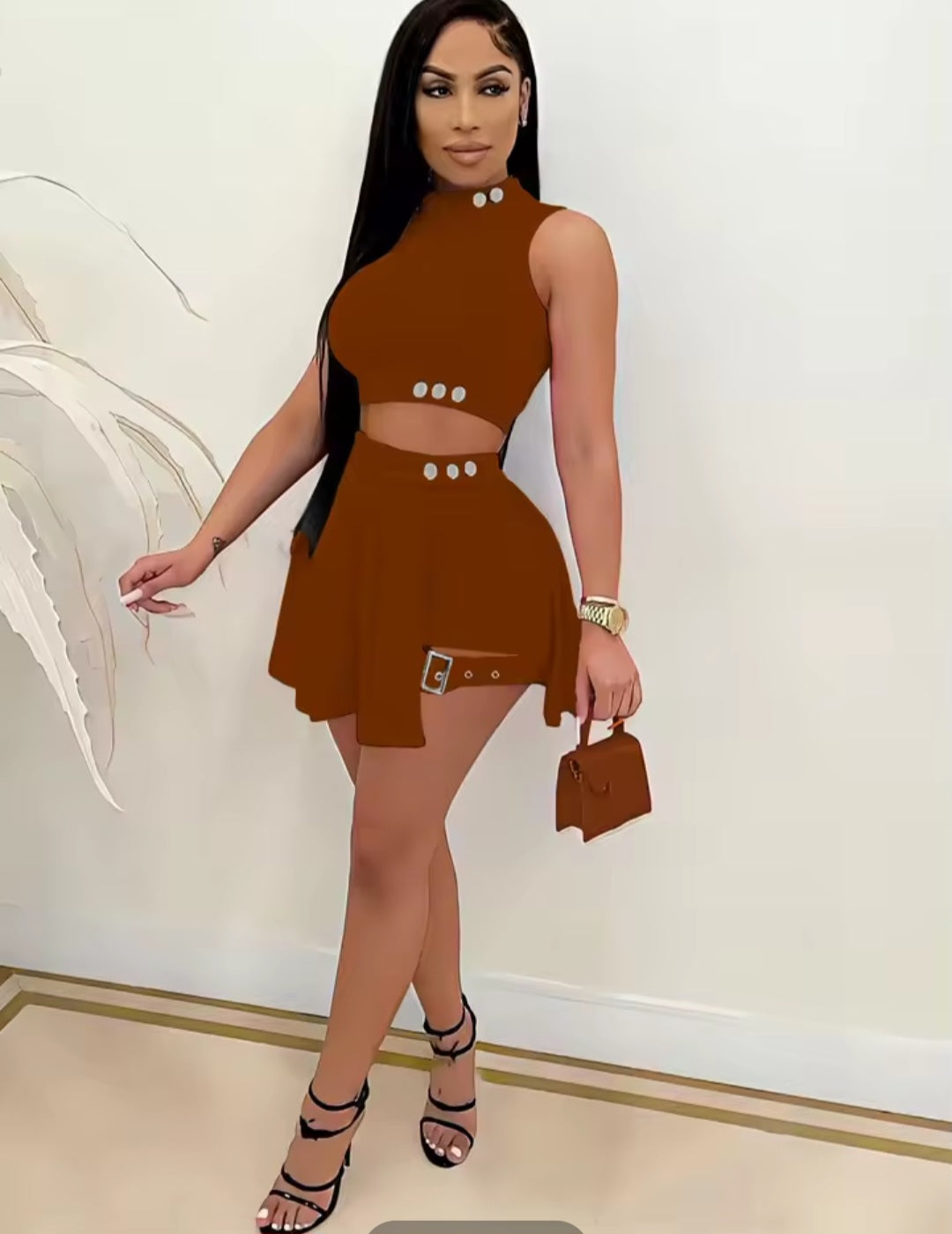 Woman wearing a brown dress with cut-out design, holding a matching handbag indoors.