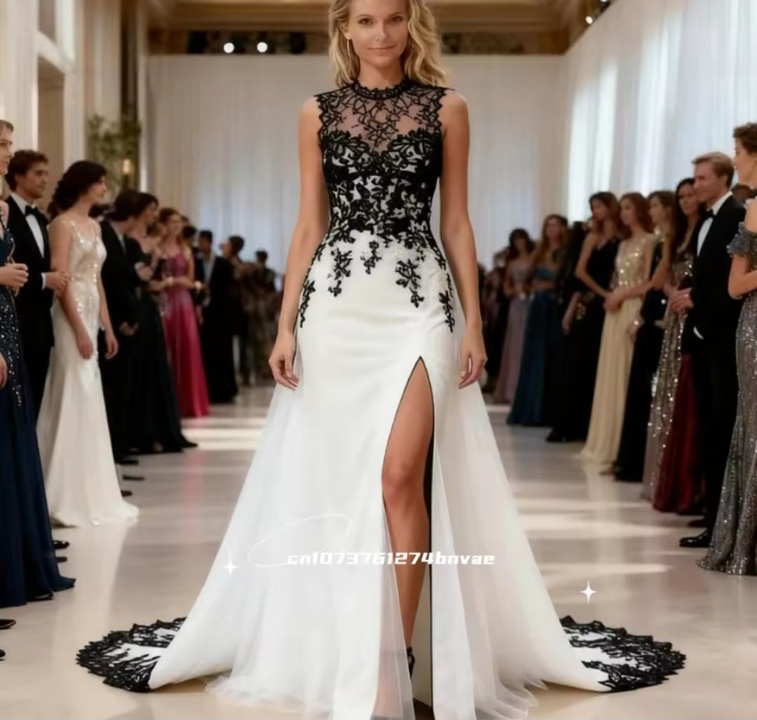 Woman in a black and white evening gown with lace details at a formal event.