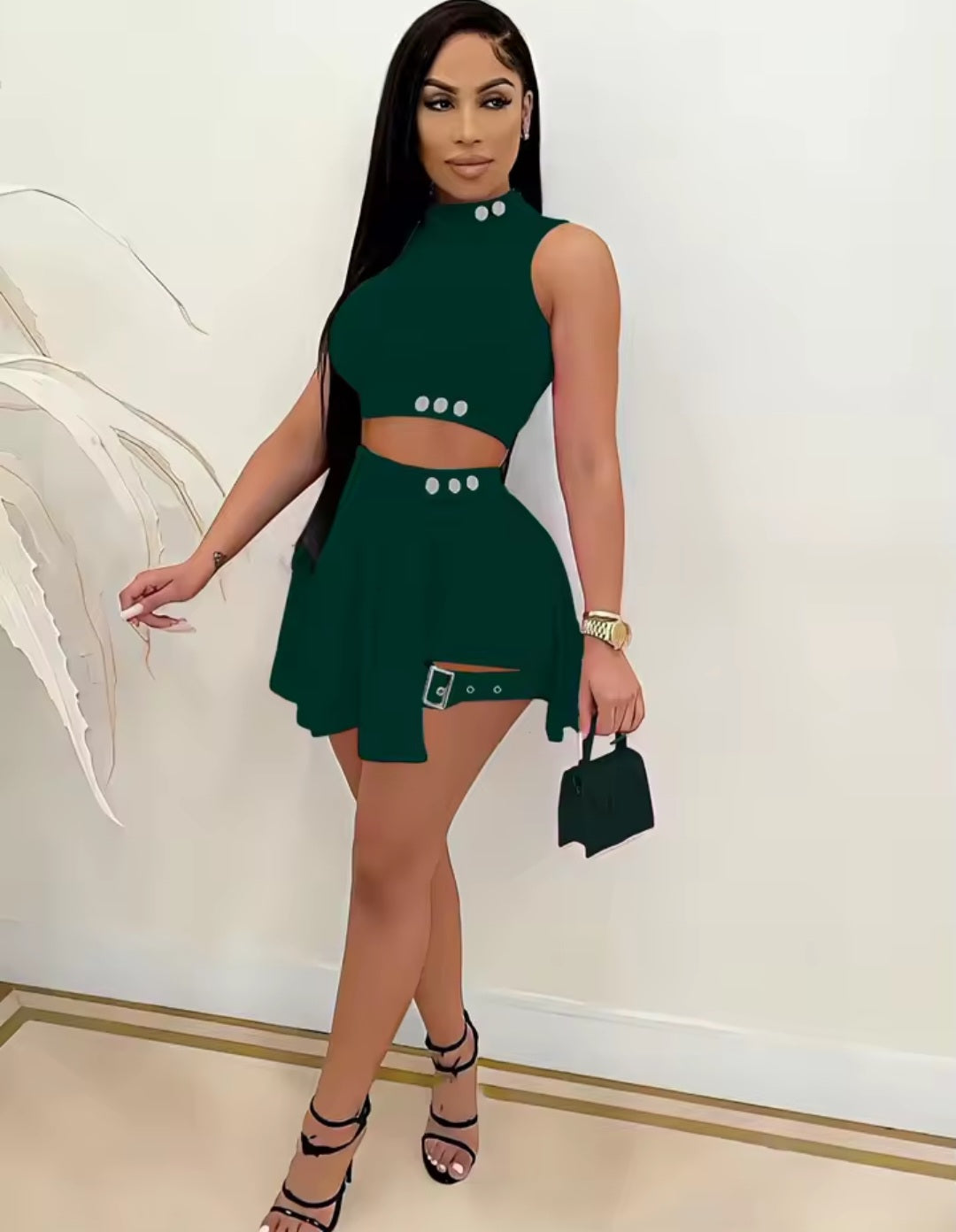 Woman wearing a green dress with cut-out design against a white wall.