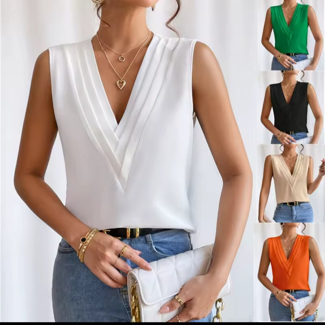 Woman wearing a white sleeveless top with a V-neckline, paired with blue jeans and holding a clutch.
