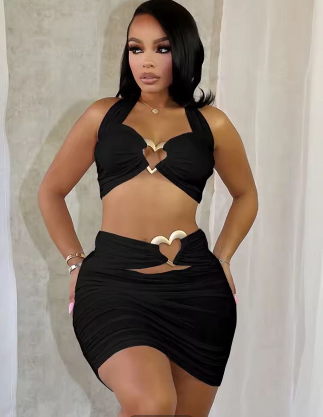 Woman wearing a black outfit with heart designs against a neutral background