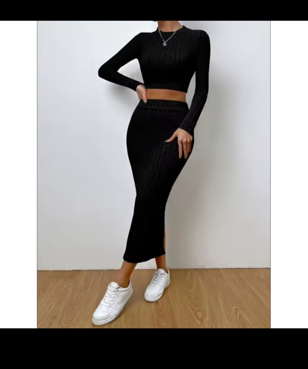 Person wearing a black outfit with white sneakers on a plain background