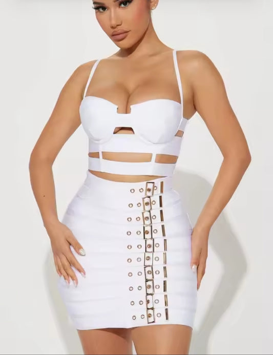 Woman wearing a white two-piece outfit with cut-out design on a plain background