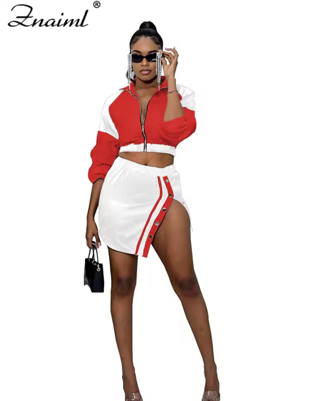 Woman wearing a red and white outfit with a matching jacket and skirt, holding a black handbag.