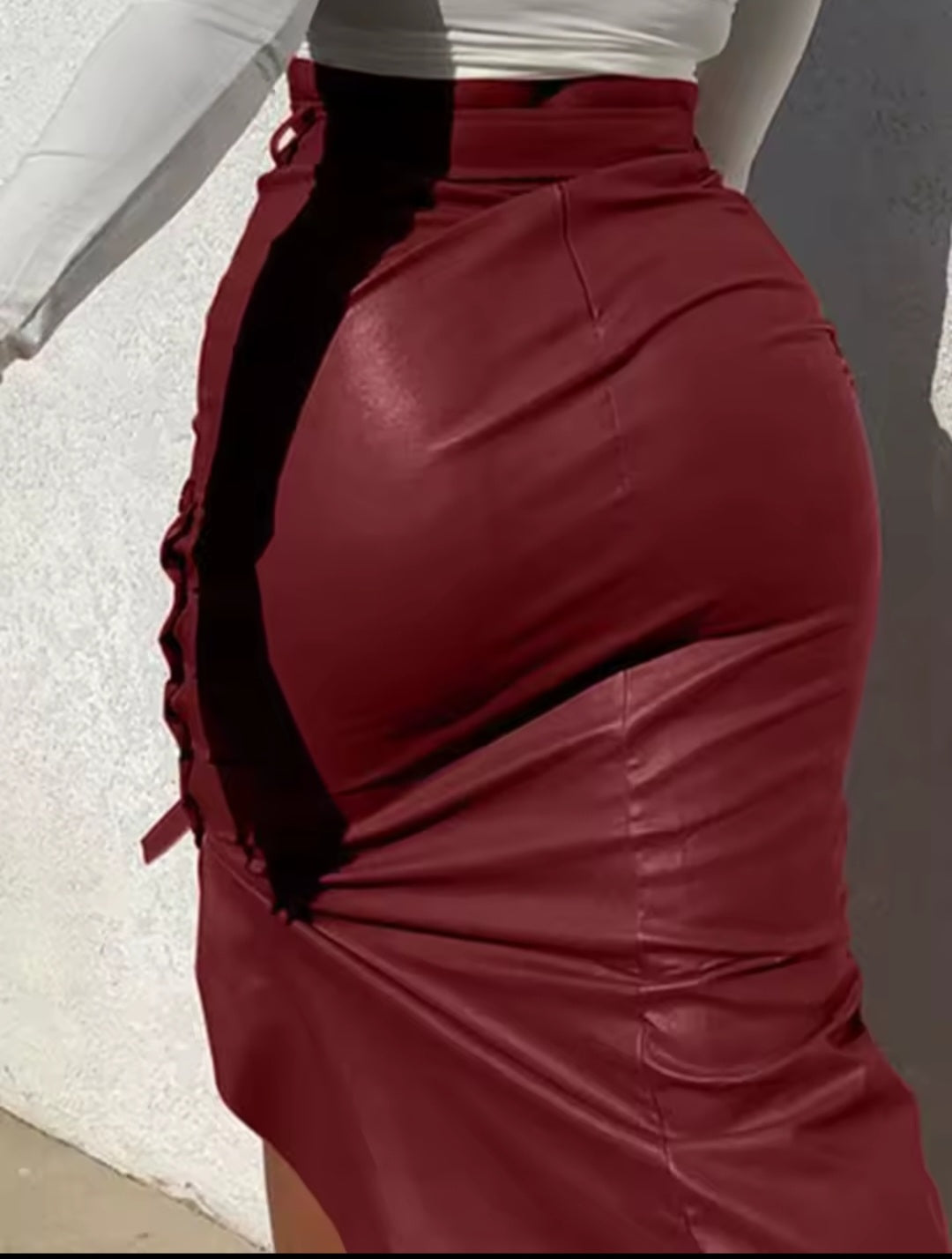 Red leather skirt with black accents worn by a person, on a neutral background