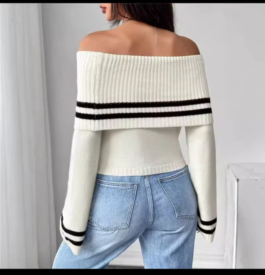 White off-shoulder sweater with black stripes worn by a person, with a plain background