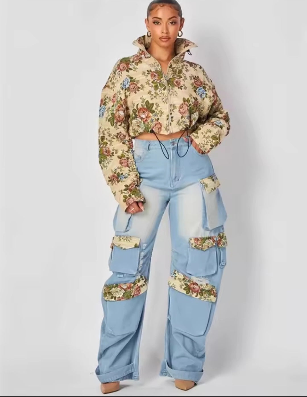 Person wearing a floral hoodie and light blue jeans with floral patches on a white background