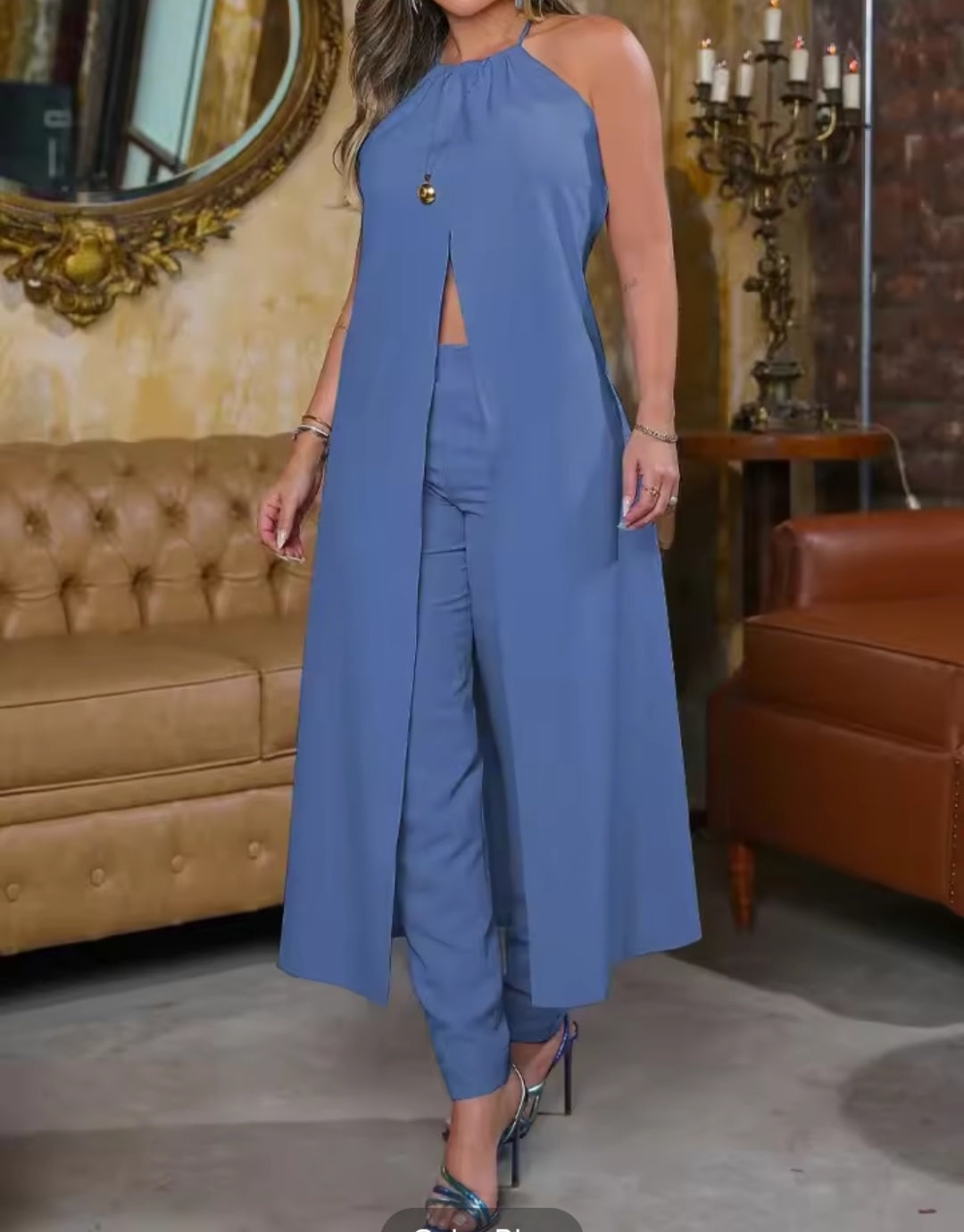 Woman wearing a blue jumpsuit in a room with a brown couch and decorative mirror.