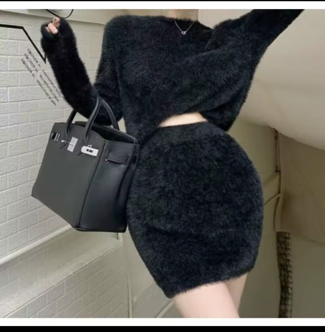 Person wearing a dark outfit holding a black handbag in an indoor setting.