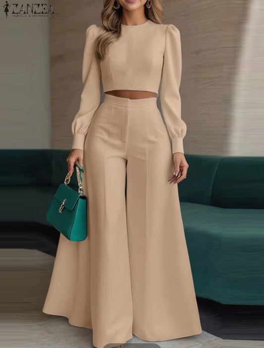 Woman wearing a beige outfit with a teal handbag in an indoor setting