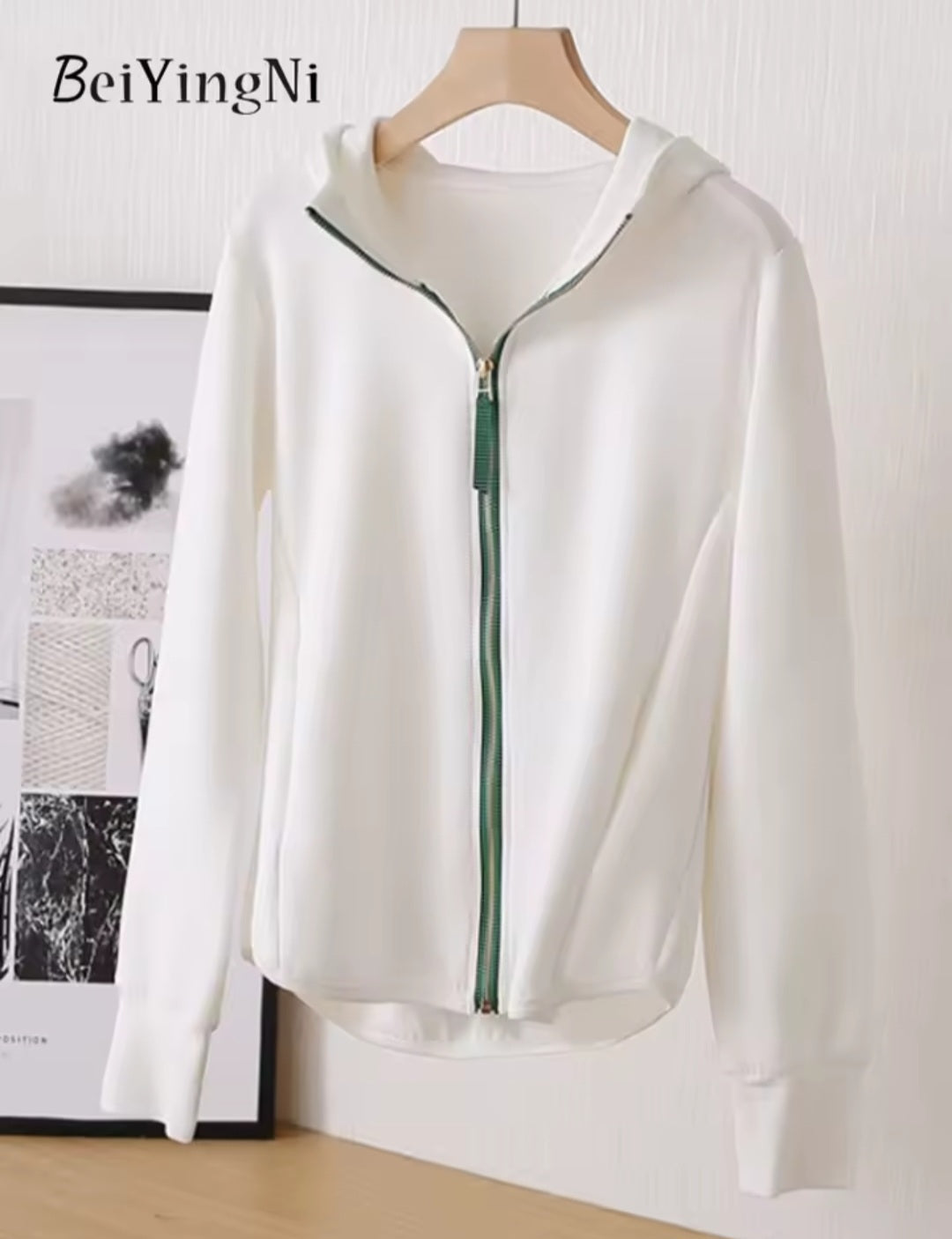 White zip-up hoodie on a hanger with a minimal background