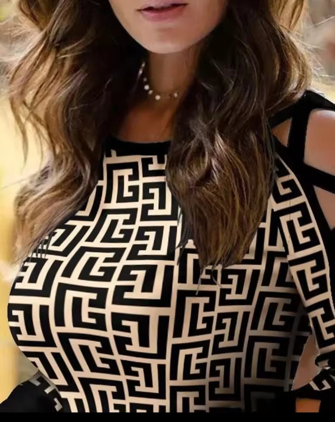 Person wearing a black and white patterned dress with cut-out shoulders.