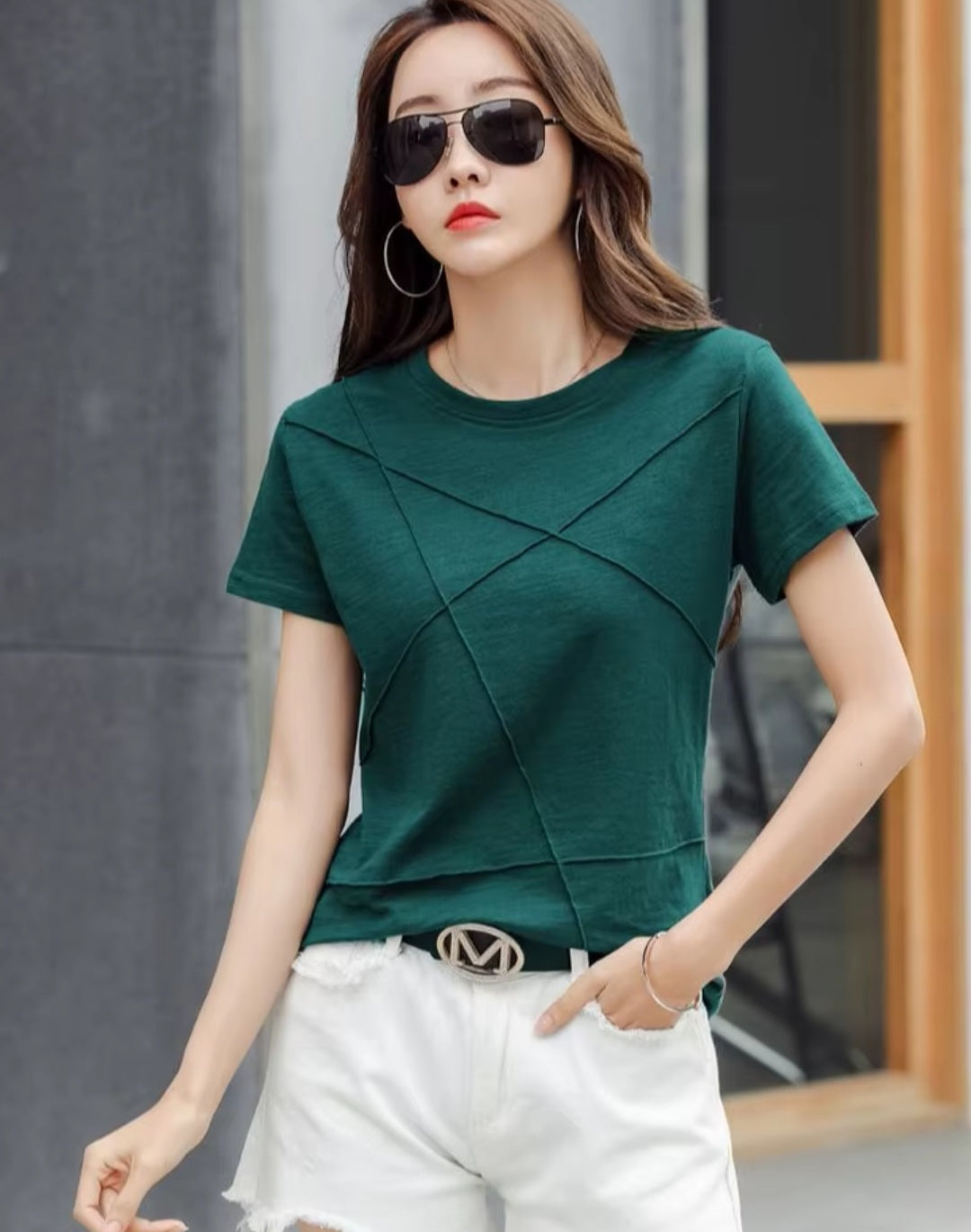 Woman wearing a green top and white shorts with sunglasses outdoors.