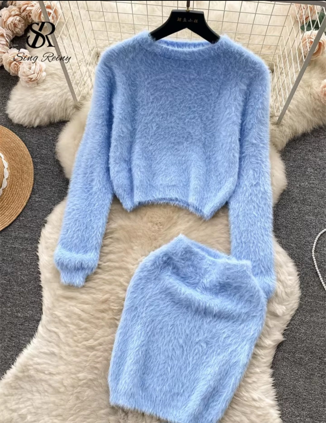 Light blue fuzzy sweater and matching hat on a fur surface with 'SR' branding.