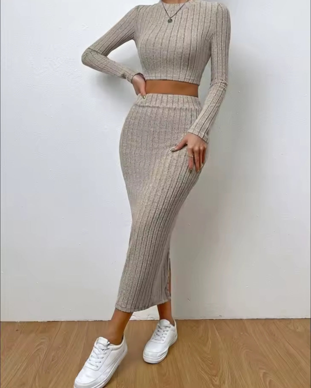 Person wearing a beige ribbed two-piece outfit with white sneakers on a plain background