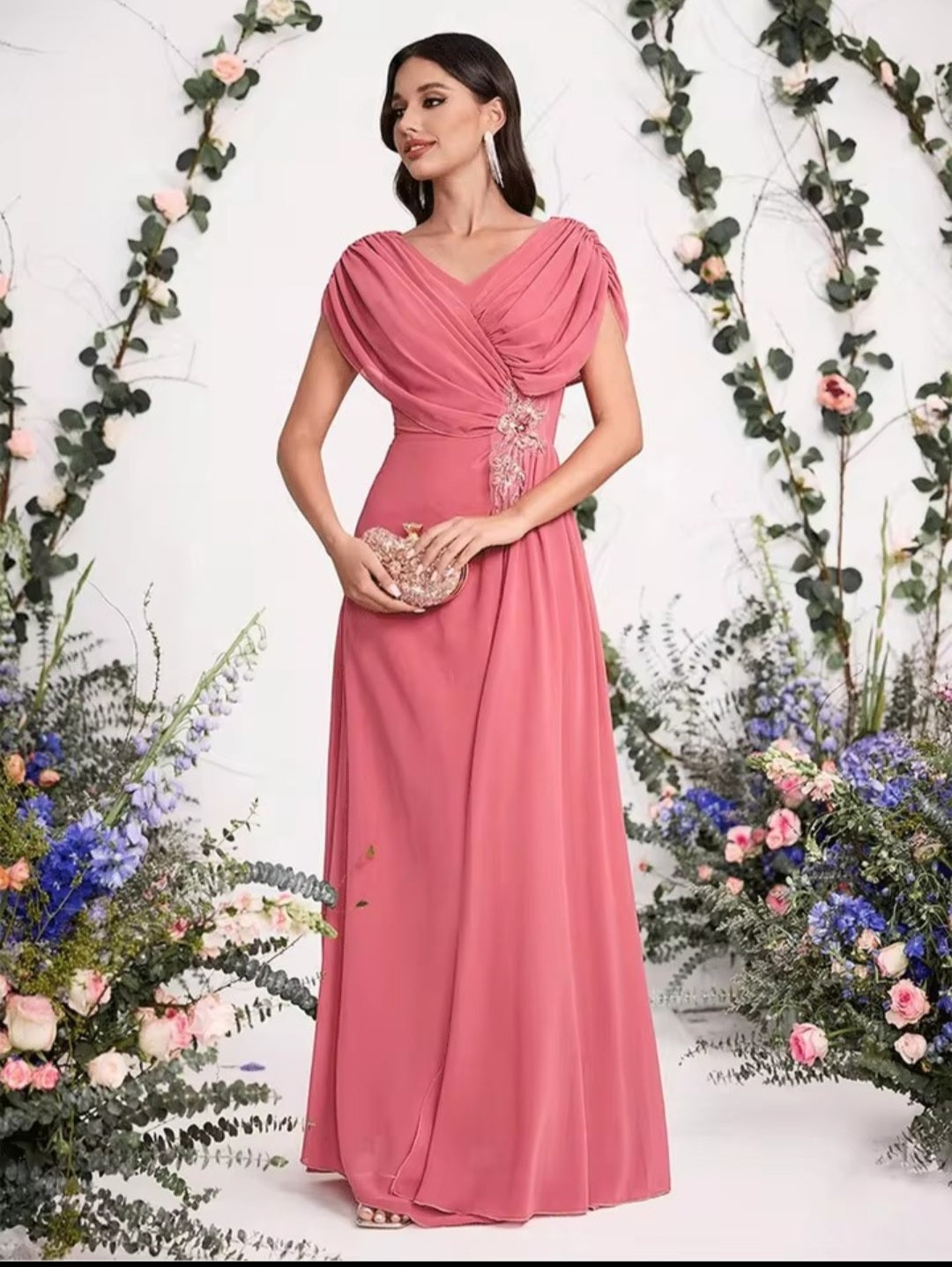 Woman in a pink evening gown standing among floral decorations