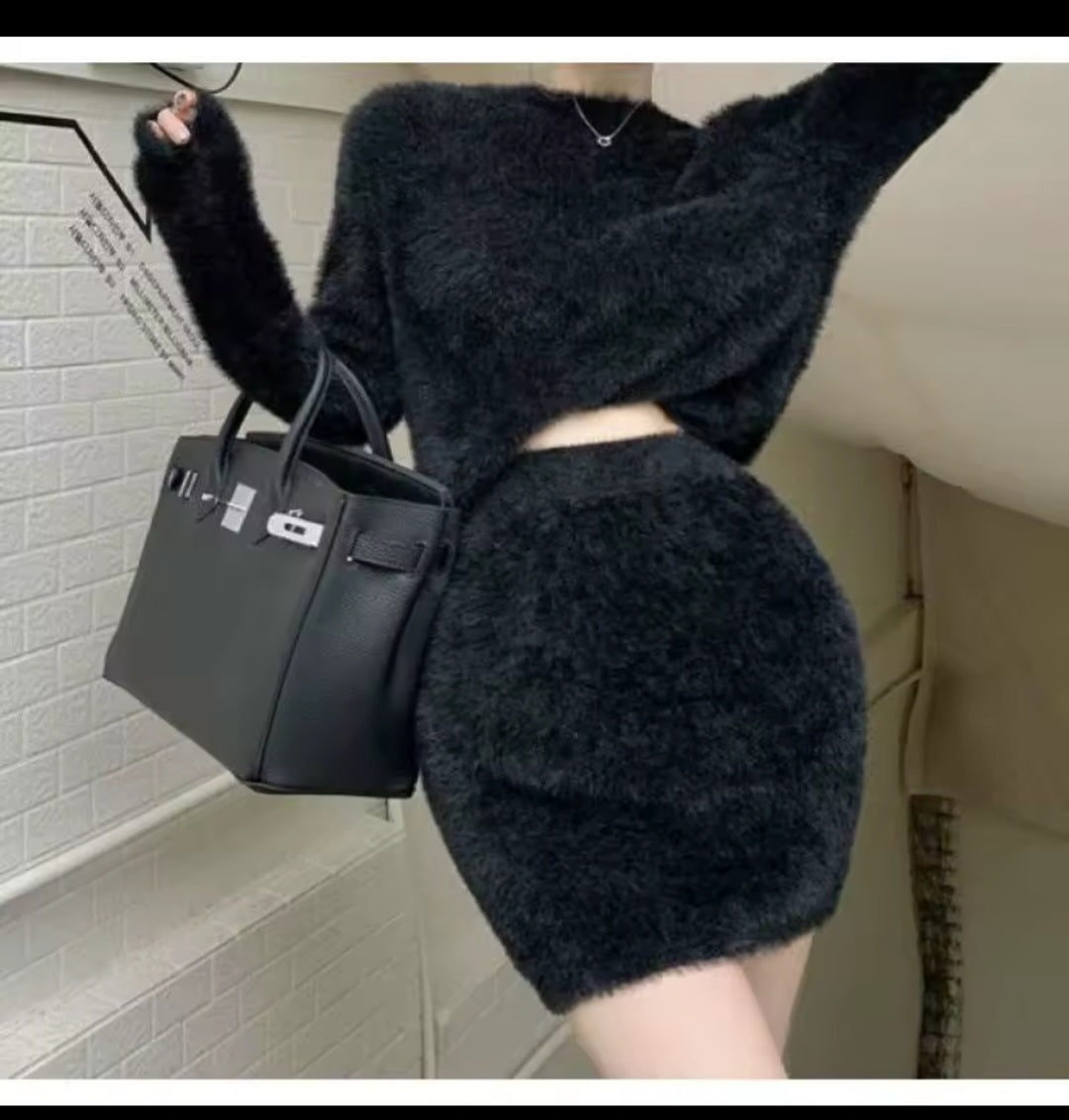 Person wearing a dark outfit with a black handbag against a neutral background