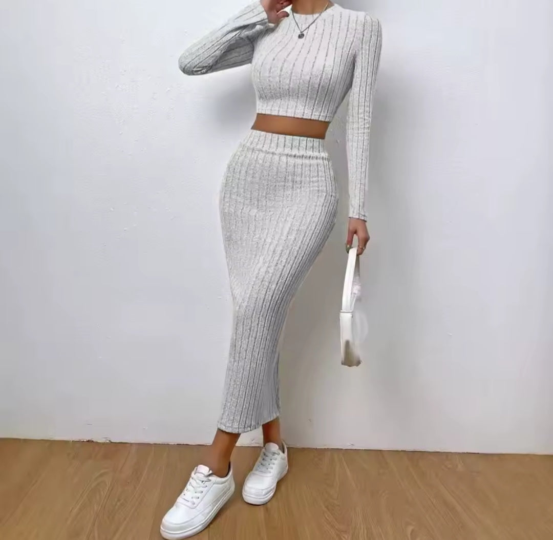 Person wearing a white ribbed knit two-piece set with white sneakers on a plain background