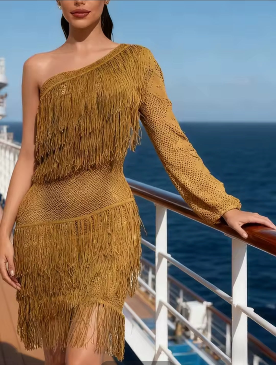 Woman wearing a mustard yellow one-shoulder fringed dress on a cruise ship deck.