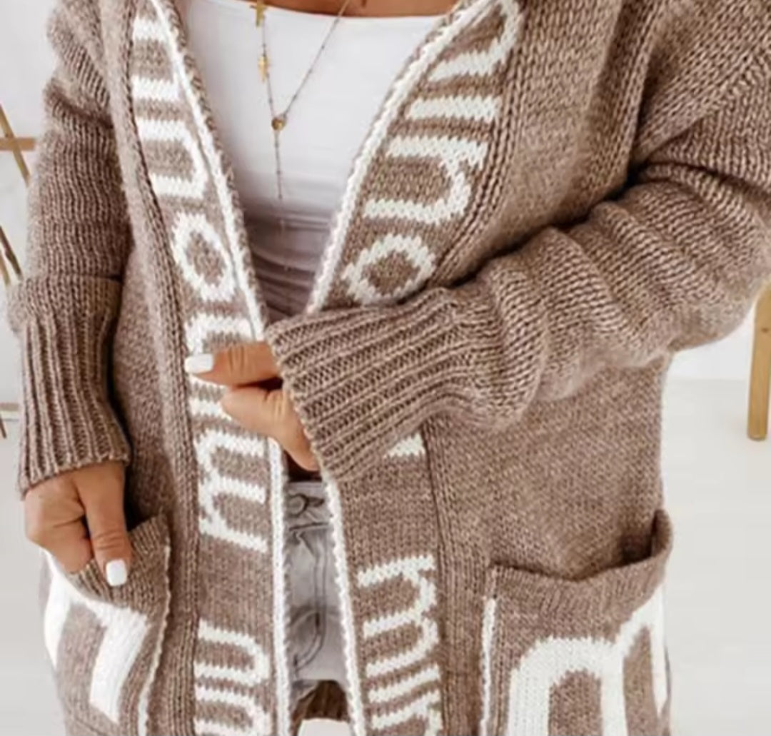 Brown knitted cardigan with white pattern worn by a person indoors.