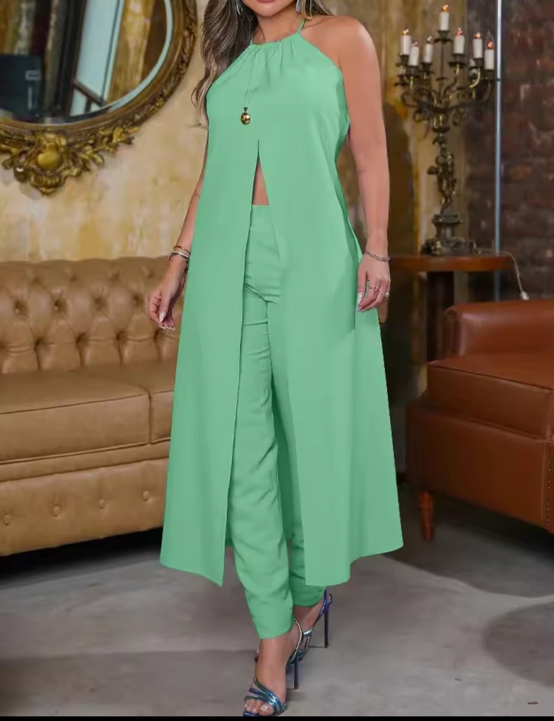 Woman wearing a green outfit in an elegant room with a mirror and candles.