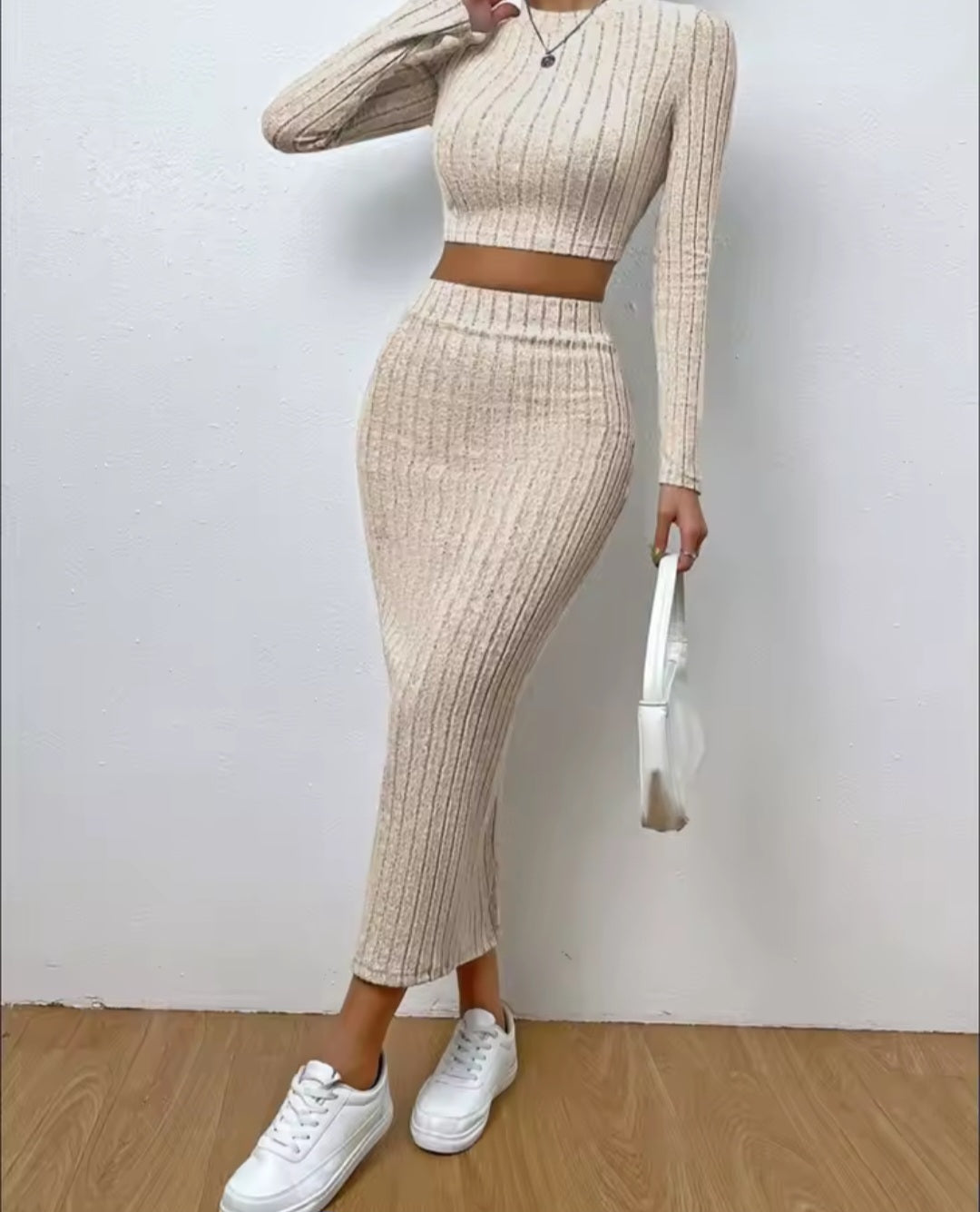 Person wearing a beige ribbed knit outfit with white sneakers against a plain background