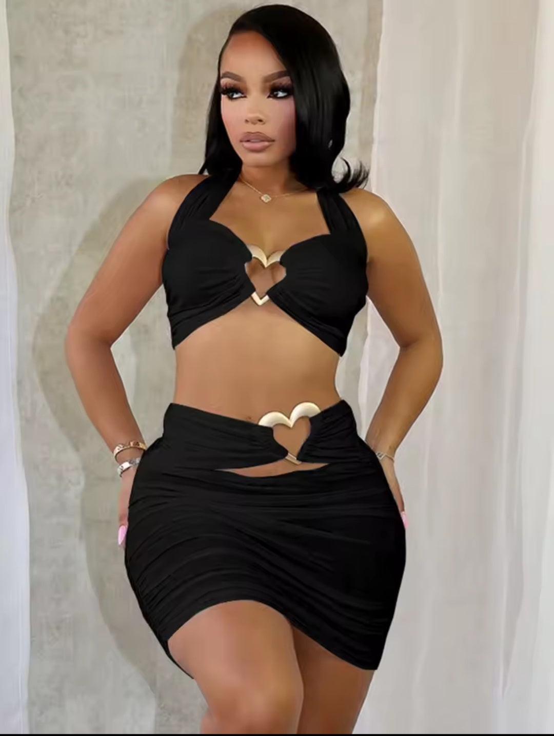 Woman wearing a black halter top and skirt with cut-out designs against a neutral background