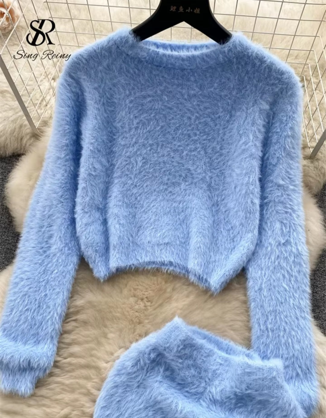 Light blue fuzzy sweater on a hanger with a textured background