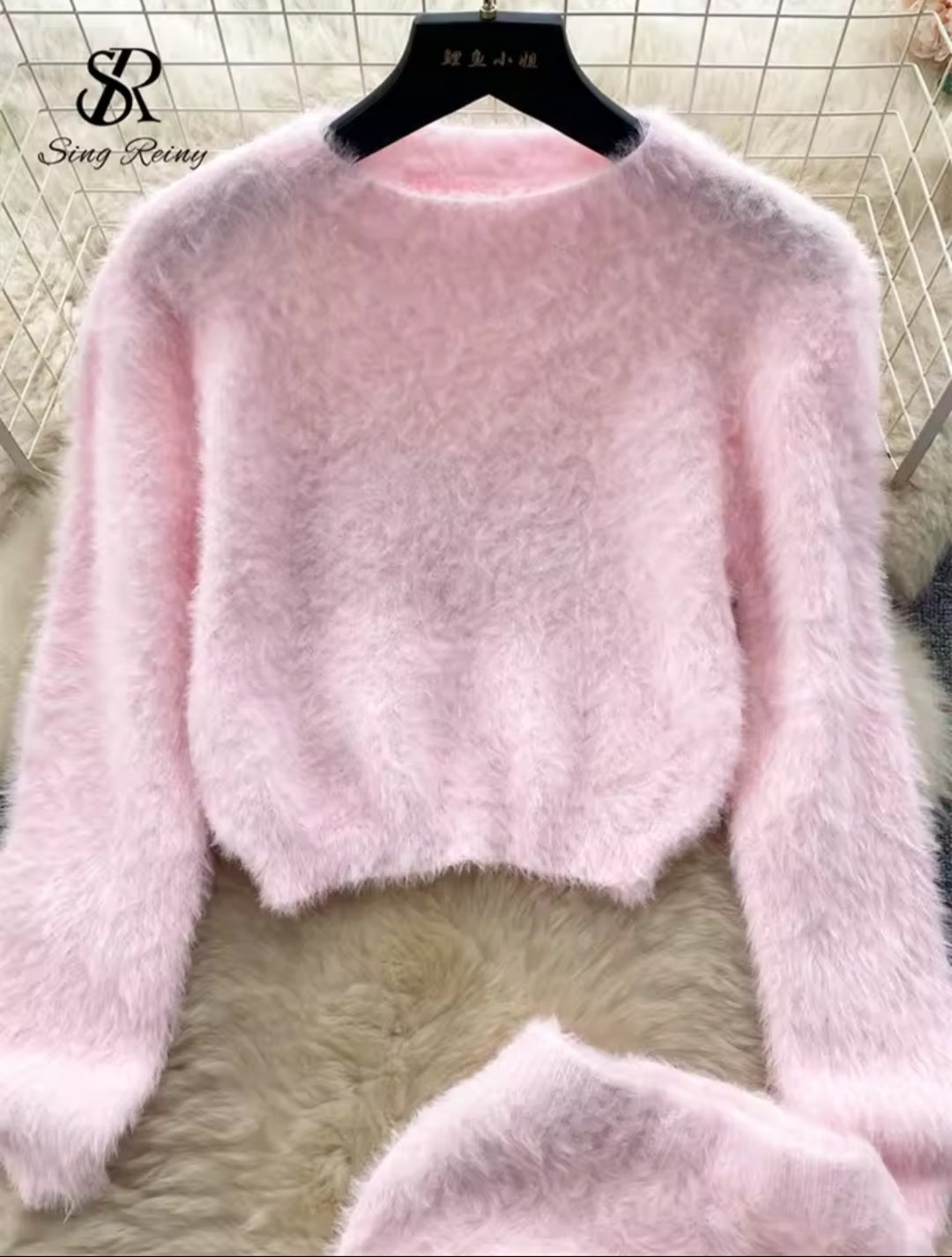 Pink fluffy sweater on a hanger with a blurred background
