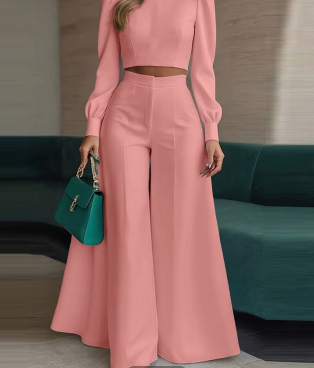 Person wearing a pink outfit holding a green handbag in an indoor setting.