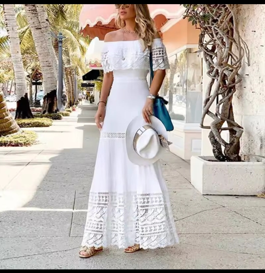 Woman in a white lace dress walking on a tropical street.