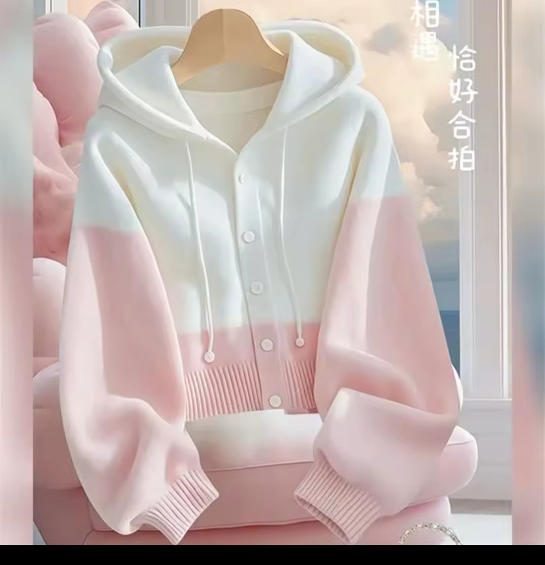 White and pink cardigan on a hanger with a blurred background