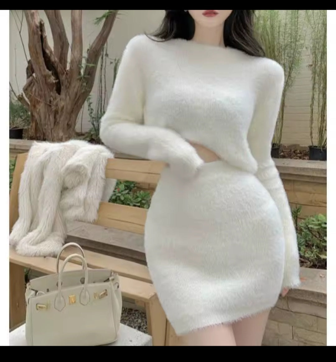 Person wearing a white textured dress with a handbag on a wooden bench outdoors.