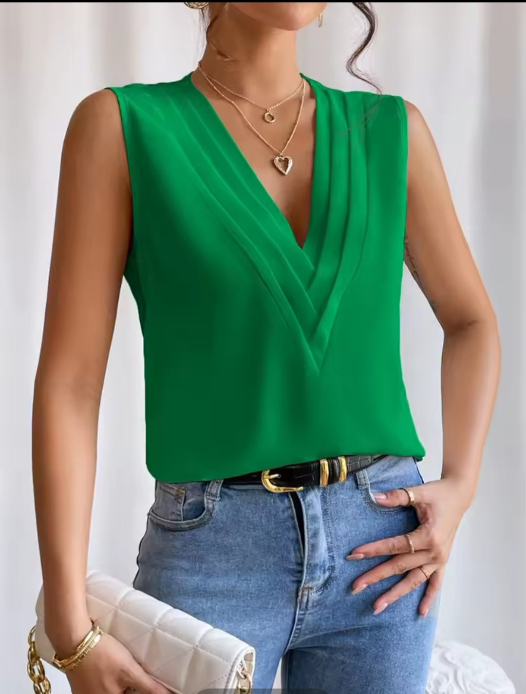 Person wearing a green sleeveless top and blue jeans with a white background