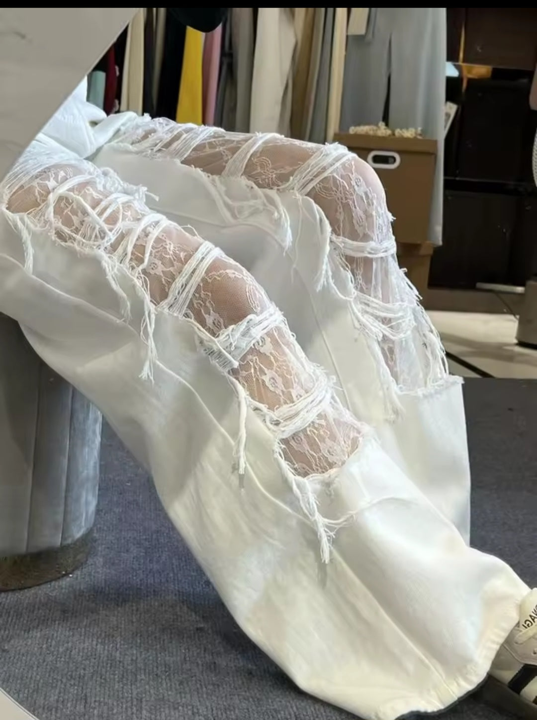 White pants with sheer lace detailing on a clothing rack.