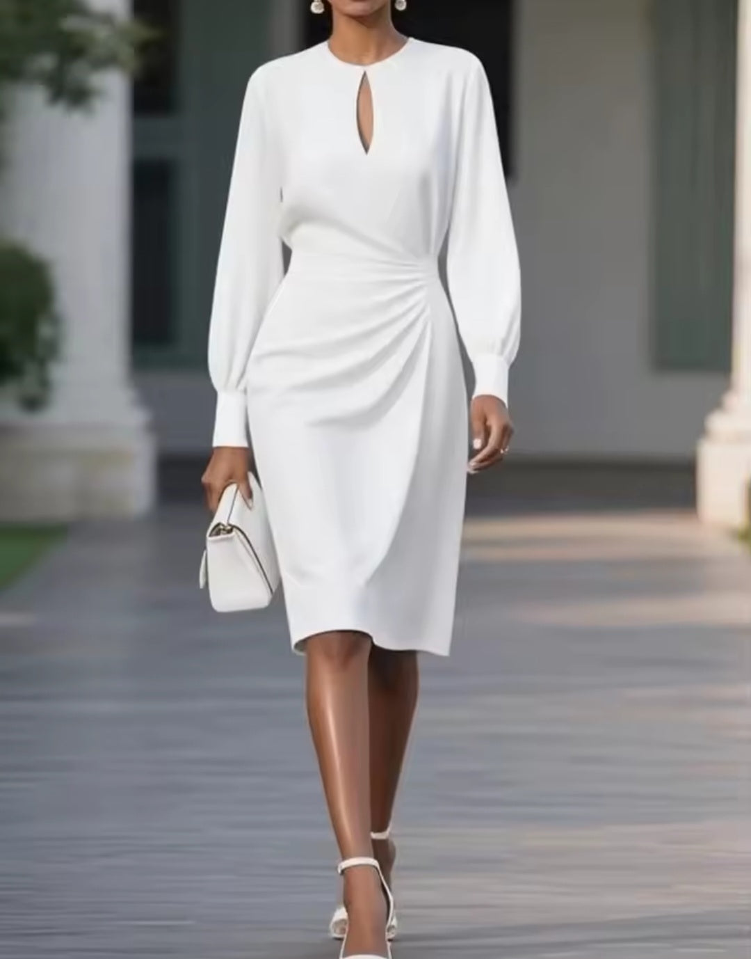 Woman in a white dress walking outdoors with a blurred background