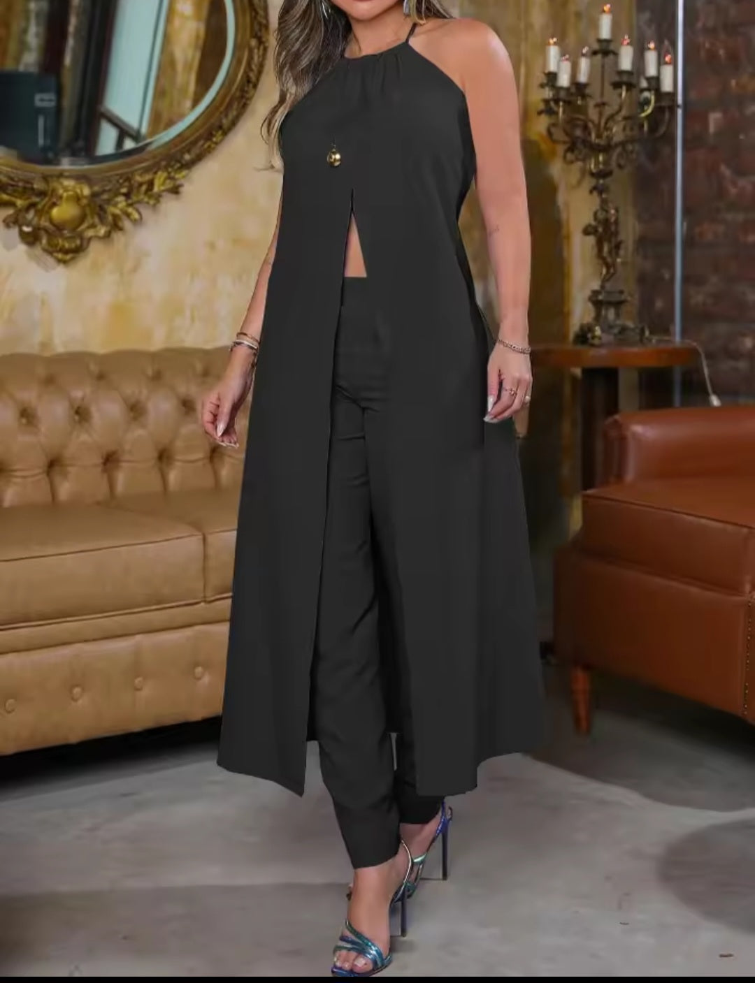 Woman wearing a black outfit in an elegant room with a mirror and candelabra.