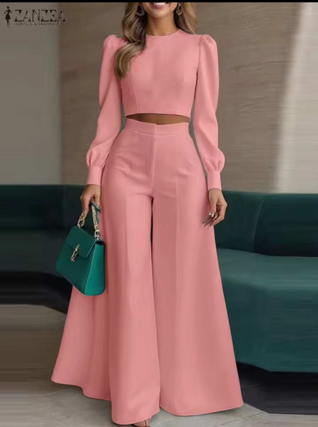 Woman wearing a pink outfit with a teal handbag in an indoor setting