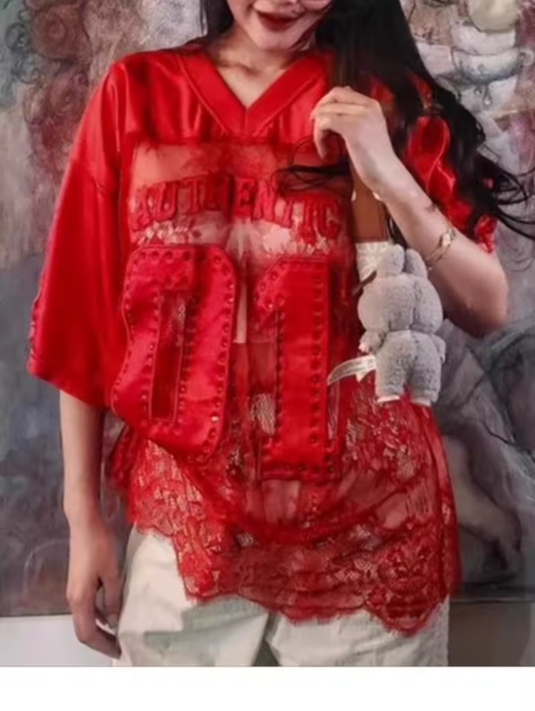 Person wearing a red outfit with text, holding a small bag.