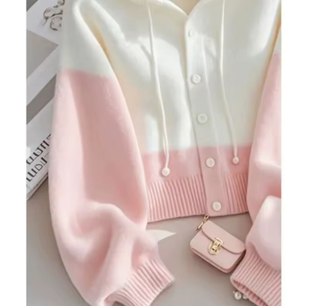 White and pink cardigan with a small pink handbag on a light surface.